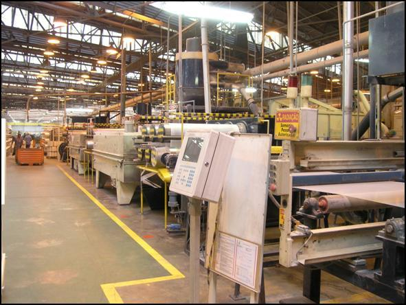 Textile manufacturing equipment and operator control panels along a production aisle.